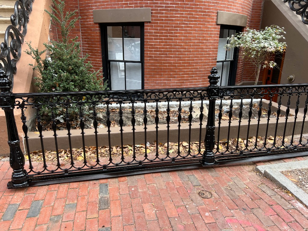 Decorative black iron fence along a brick walk — ornamental metalwork