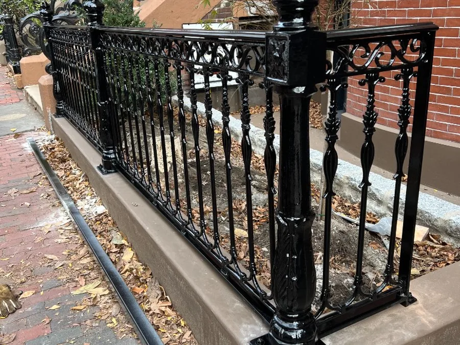 Decorative black iron fence on a brick sidewalk