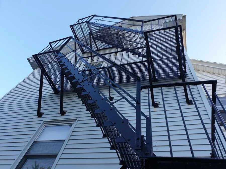 Black steel fire escape installed on a multi-story building