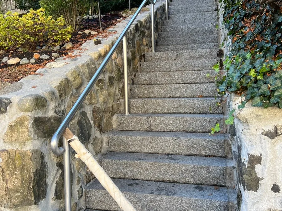 Long exterior stair railing on stone steps for access egress