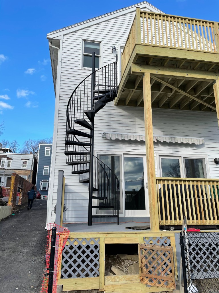 Exterior black metal spiral staircase with diamond-plate treads — deck-to-deck Massachusetts install
