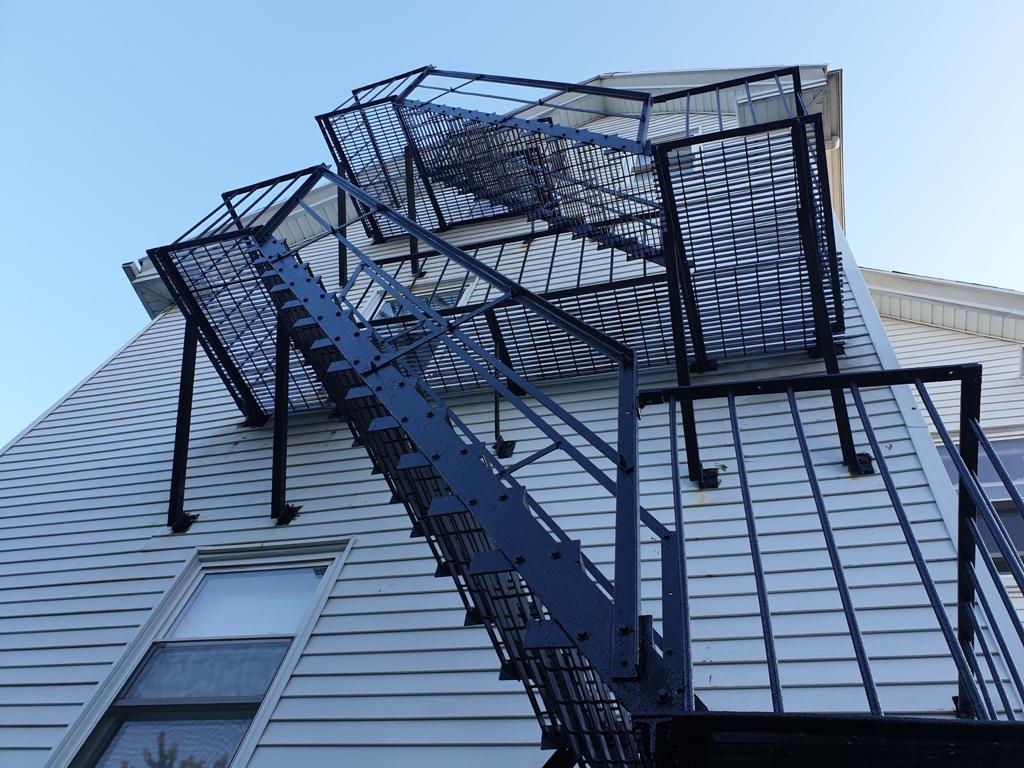 Multi-story steel fire escape with open grating stairs and railings — Massachusetts building